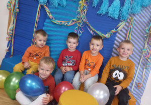 Chłopcy z balonami pozują do zdjęcia grupowego.
